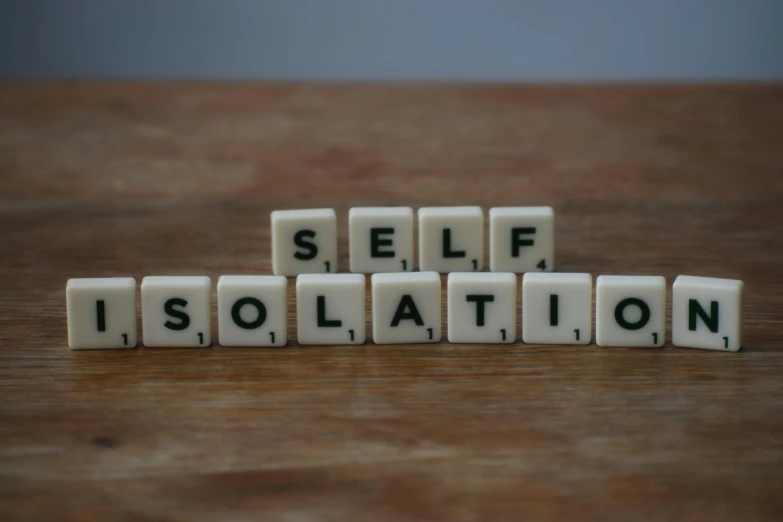 the word self isolation spelled in scrabbles on a wooden table, inspired by Sarah Lucas, pexels, 1 6 x 1 6, solitude, squad, healthcare