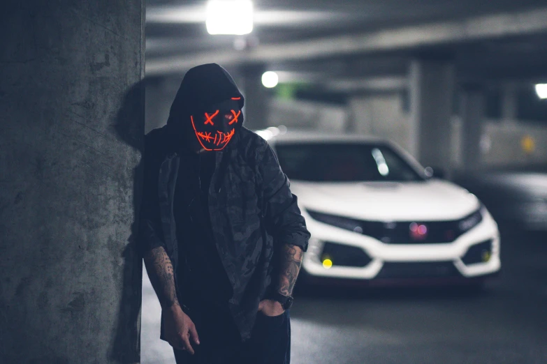 a man wearing a mask standing in a parking garage, an album cover, unsplash contest winner, lyco art, red leds, jack - o'- lantern, custom headlights, techwear clothes