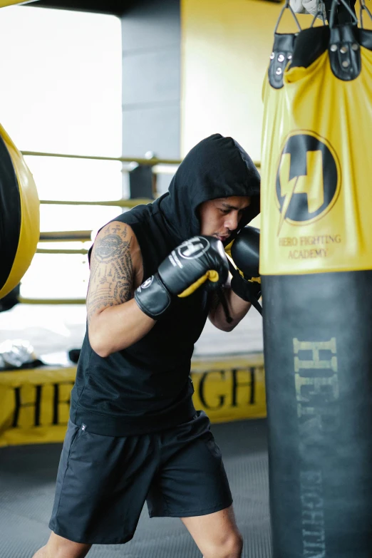 a man standing next to a punching bag, happening, wearing a yellow hoodie, profile image, hero, sweat drops