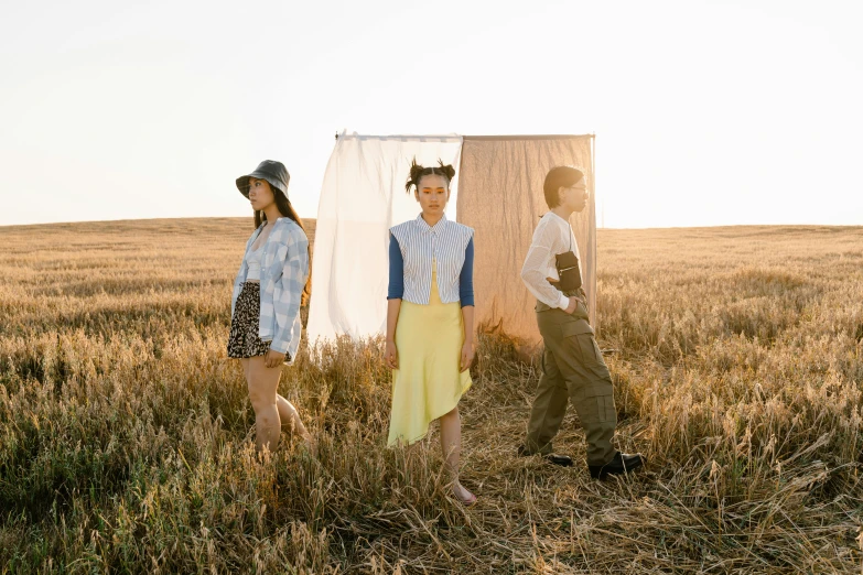 a group of people standing in a field, an album cover, fashion editorial, 3 actors on stage, prairie, lulu chen