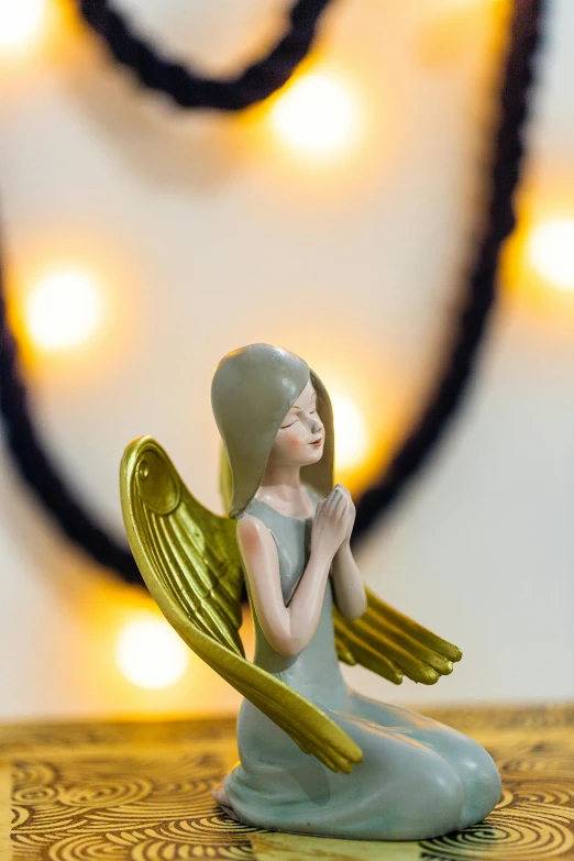 a figurine of an angel sitting on a table, an art deco sculpture, pexels contest winner, happening, golden heavenly lights, grey, made of glazed, indoor picture