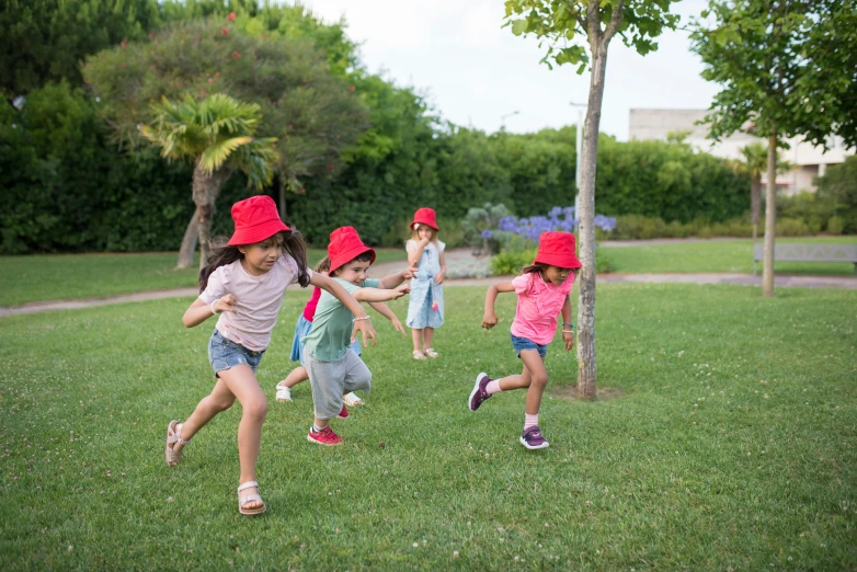 a group of young children playing a game of frisbee, inspired by Elsa Beskow, pexels contest winner, red cap with a capital m, bucket hat, bushes, running sequence