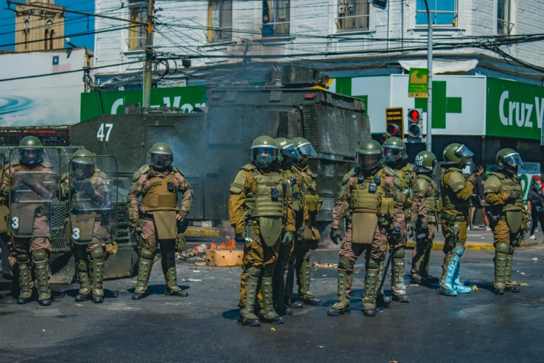 a group of soldiers standing in the middle of a street, by Gina Pellón, pexels contest winner, quito school, violent protest, background image, green and brown clothes, explosions in the background
