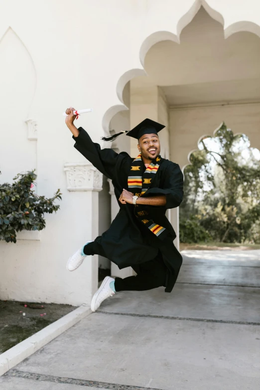 a man in a graduation gown jumping in the air, by Stokely Webster, curated collections, highly upvoted, black, smiling