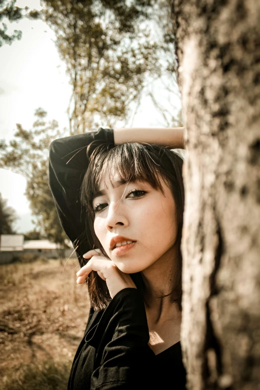 a woman leaning against a tree in a field, inspired by Yu Zhiding, pexels contest winner, realism, young cute wan asian face, ((portrait)), portrait rugged girl, black