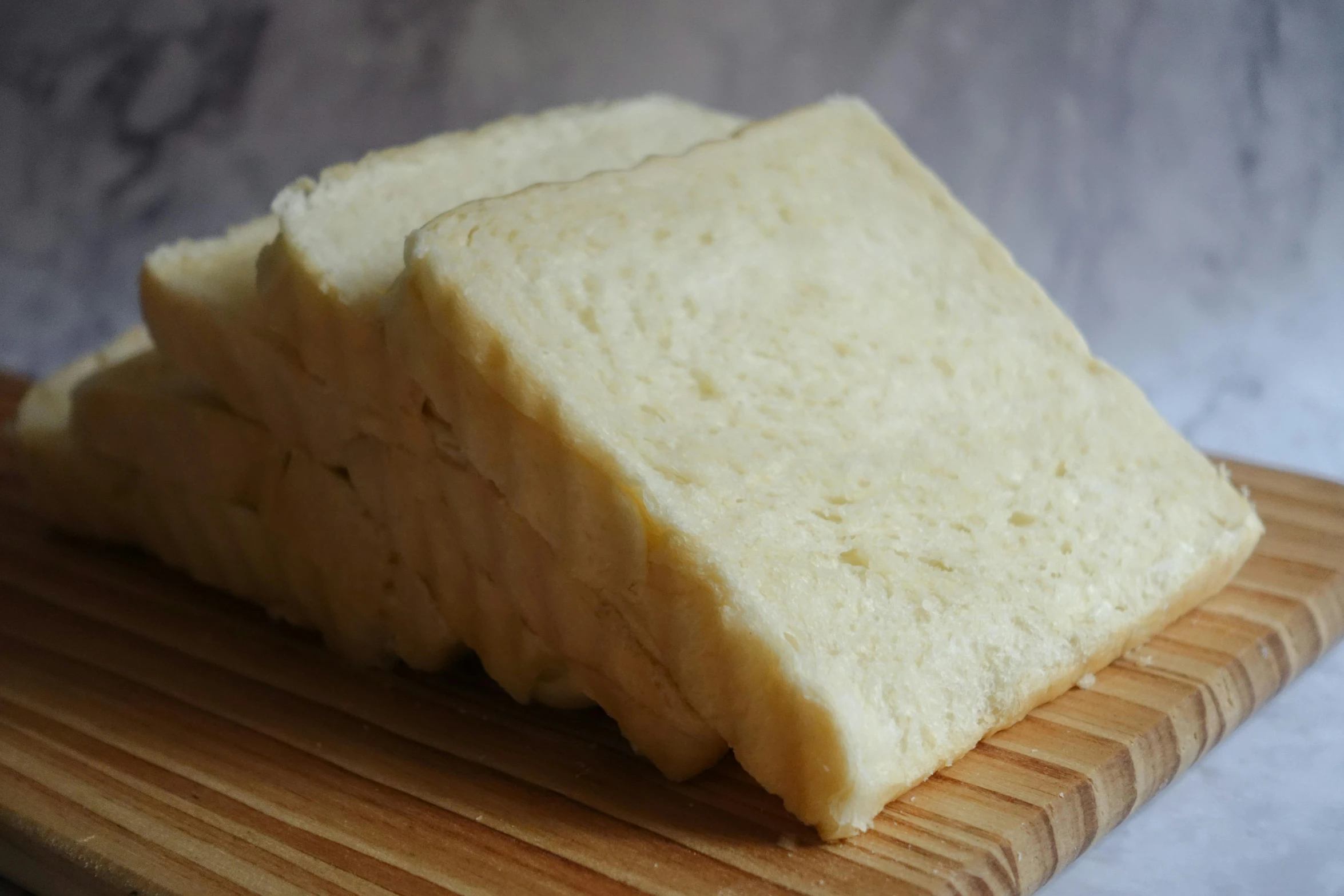 a pile of cheese sitting on top of a wooden cutting board, by Jessie Algie, unsplash, mingei, white powder bricks, super fluffy, sandwich with fried tofu, portrait image