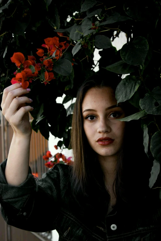 a woman holding a flower in front of her face, an album cover, inspired by Elsa Bleda, unsplash, vine covered, dilraba dilmurat, red flowers, portrait of vanessa morgan