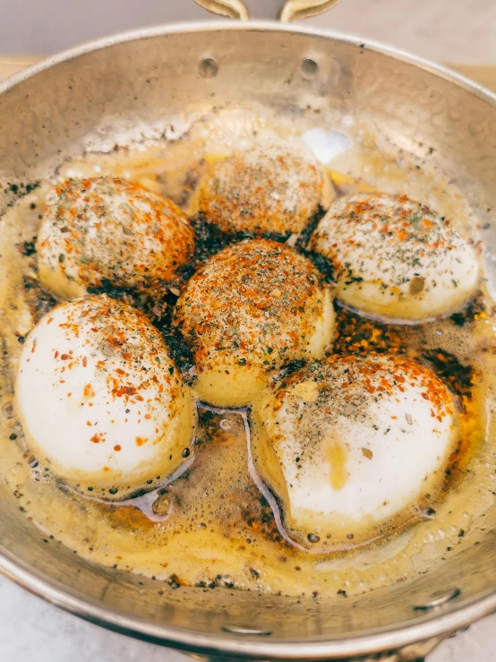 a frying pan filled with eggs on top of a stove, by Adam Marczyński, hurufiyya, dumplings on a plate, 5k, mozzarella, warm summer nights