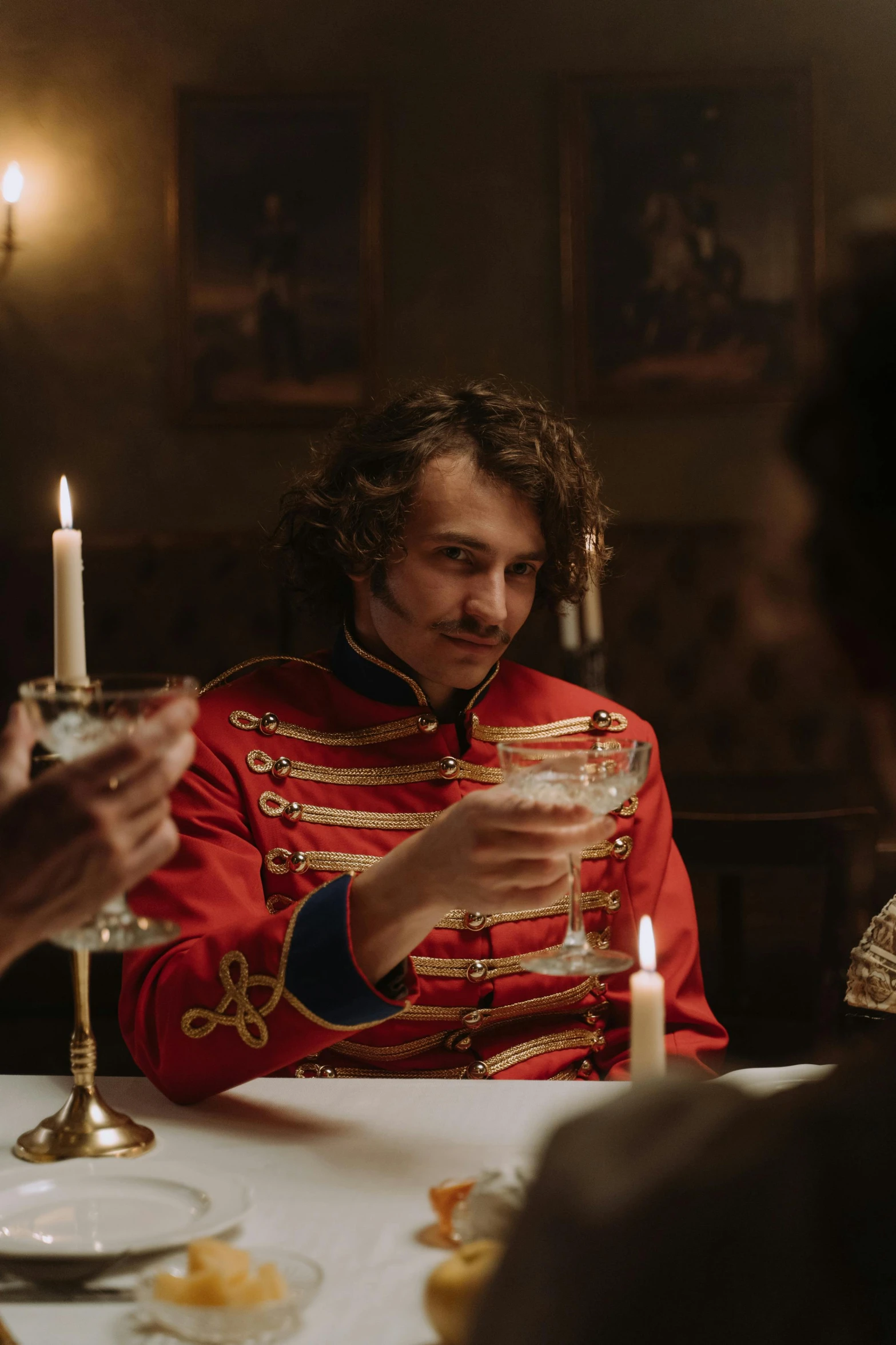 a group of people sitting around a dinner table, a portrait, inspired by Jean-Louis-Ernest Meissonier, pexels contest winner, rococo, wearing a red captain's uniform, movie still frame, robert sheehan, drinking at the bar