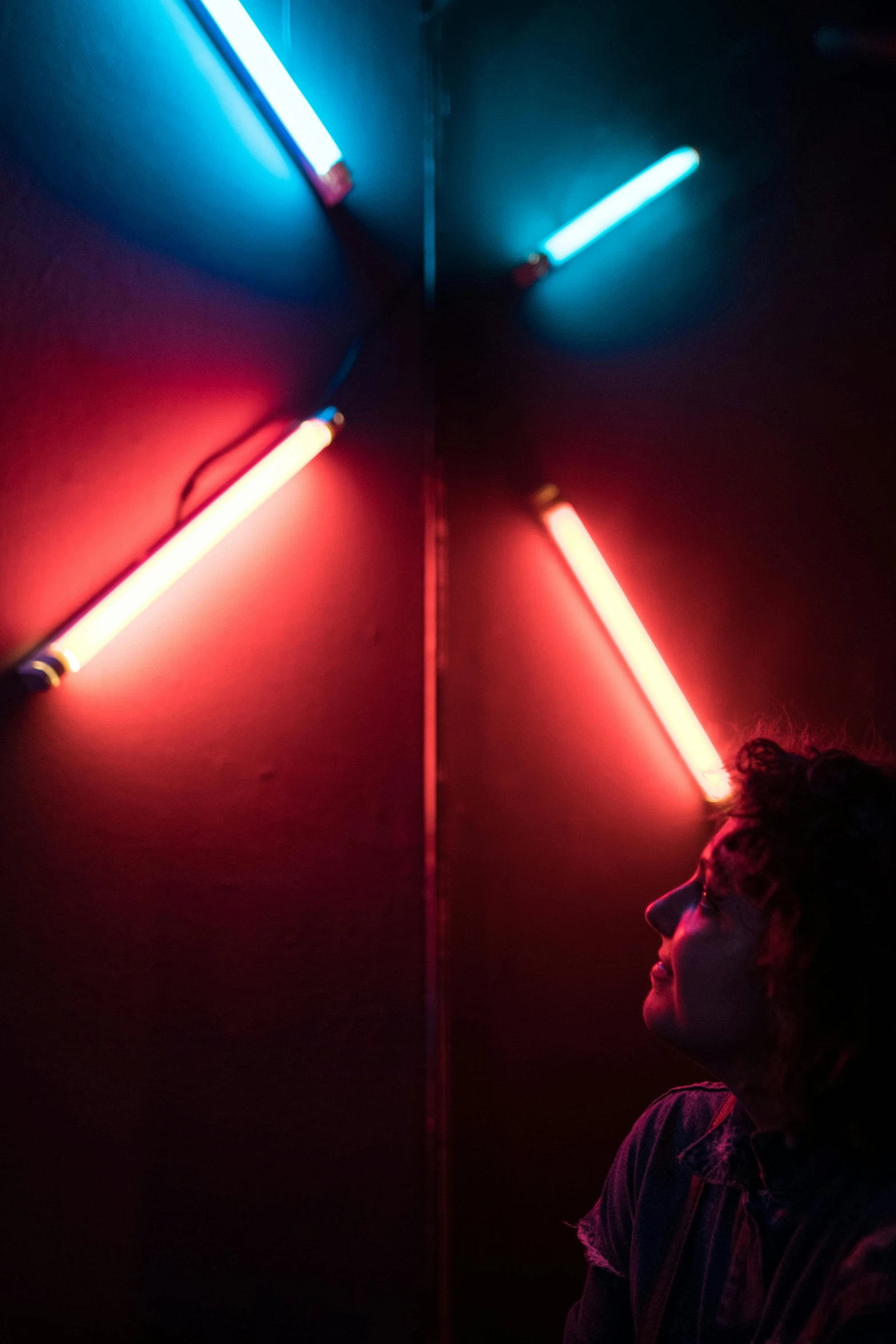 a person standing in front of a wall with neon lights, red light bulbs, iridescent tubes, fluorescent light, contemplating