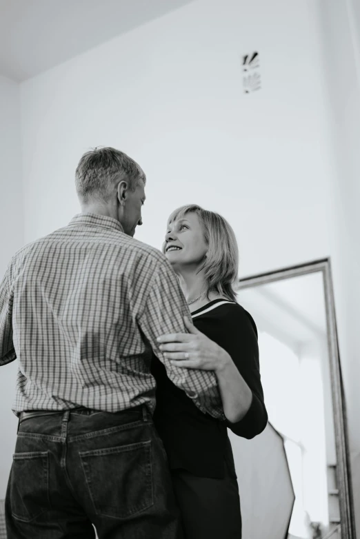 a black and white photo of a man and a woman, by Lynn Pauley, unsplash, happening, couple dancing, middle - age, standing in corner of room, promo image