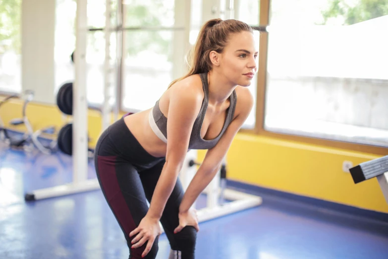 a woman holding a kettlebell in a gym, pexels contest winner, figuration libre, hunched over, avatar image, wearing yellow croptop, girl running