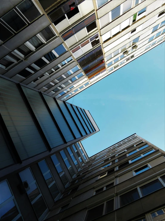 a very tall building with lots of windows, a photo, inspired by Leandro Erlich, unsplash, view from below, square, photo of zurich, ignant