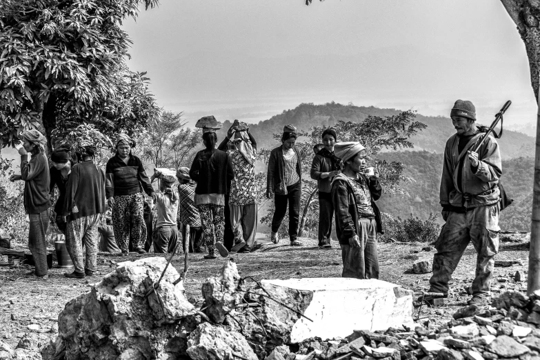 a group of people standing around a tree, a black and white photo, pexels contest winner, happening, standing atop a pile of rubble, villagers busy farming, on the mountain, earthquake destruction