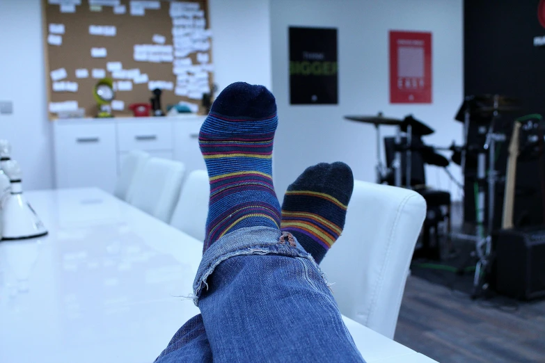 a person with their feet up on a table, pexels, in the office, striped socks, behind the scenes, deep colour