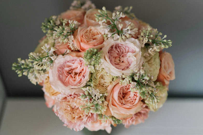a close up of a bouquet of flowers on a table, in shades of peach, soft round features, persian princess, subtle detailing