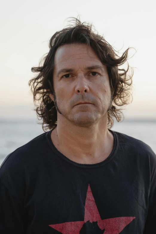 a man standing in front of a body of water, an album cover, by James Morris, headshot portrait, p cattaneo, 4 5 yo, lachlan bailey