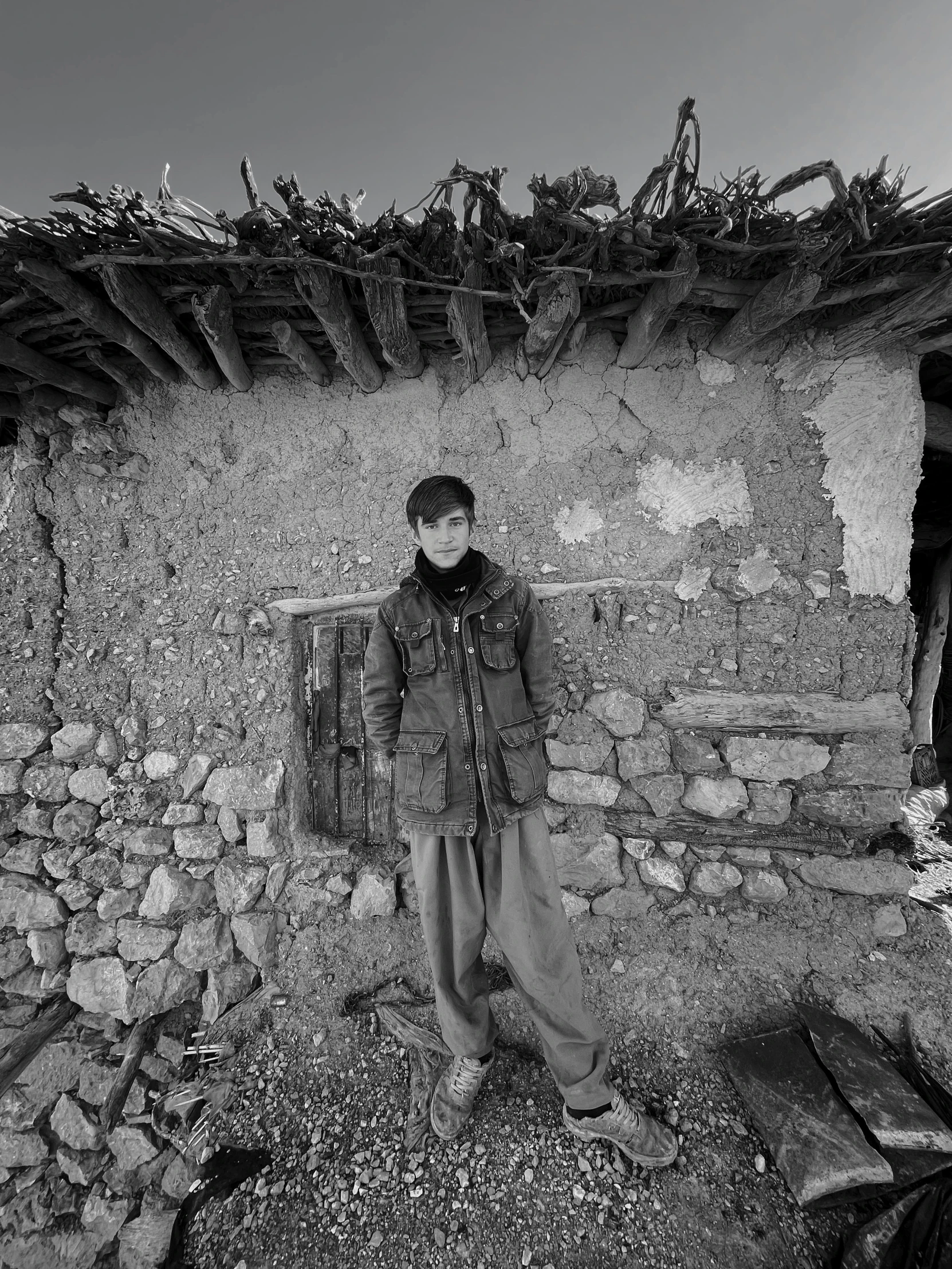 a man standing in front of a stone building, by Kevin Connor, 14 yo berber boy, abandoned photograph, jingna zhang, marc