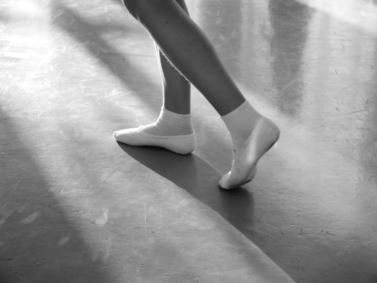 a black and white photo of a ballerina's feet, wearing white leotard, schools, sunshine, dance scene