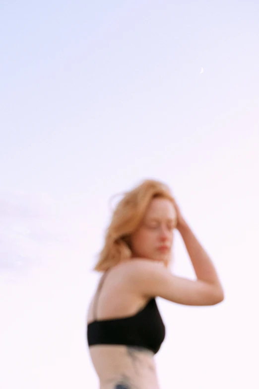 a woman standing on a beach holding a surfboard, unsplash, happening, blurry face, looking at the sky, ellie bamber, medium format. soft light