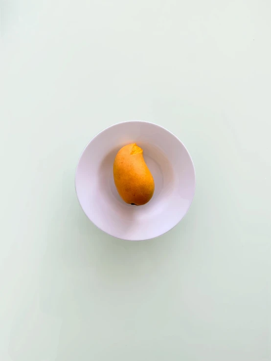 an orange in a white bowl on a table, inspired by jeonseok lee, minimalism, mango, smaller mouth, without duplicate image, yellow