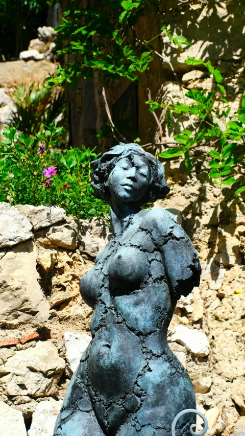 a statue of a woman sitting on top of a rock, inspired by Aristide Maillol, rotting black clay skin, marbella, beautiful surroundings, close up portrait bust of woman