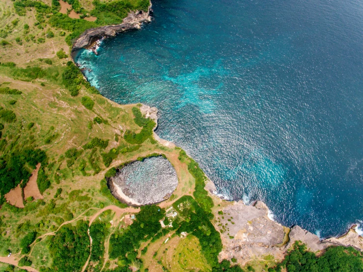 a large body of water next to a lush green hillside, a digital rendering, pexels contest winner, les nabis, caribbean, shell craters, drone photo, thumbnail