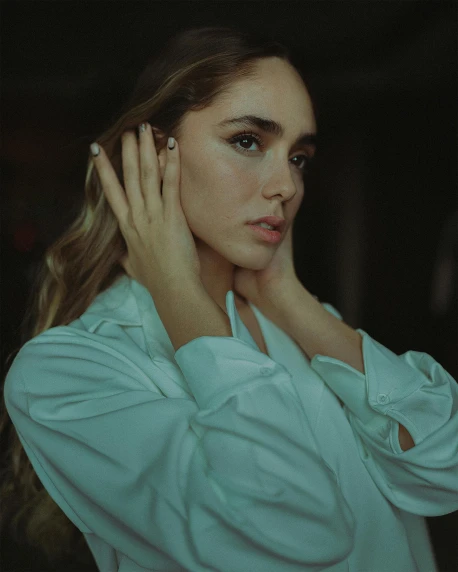 a woman in a white shirt posing for a picture, inspired by Elsa Bleda, trending on pexels, asher duran, soft lighting, robe. perfect faces, hands in her hair