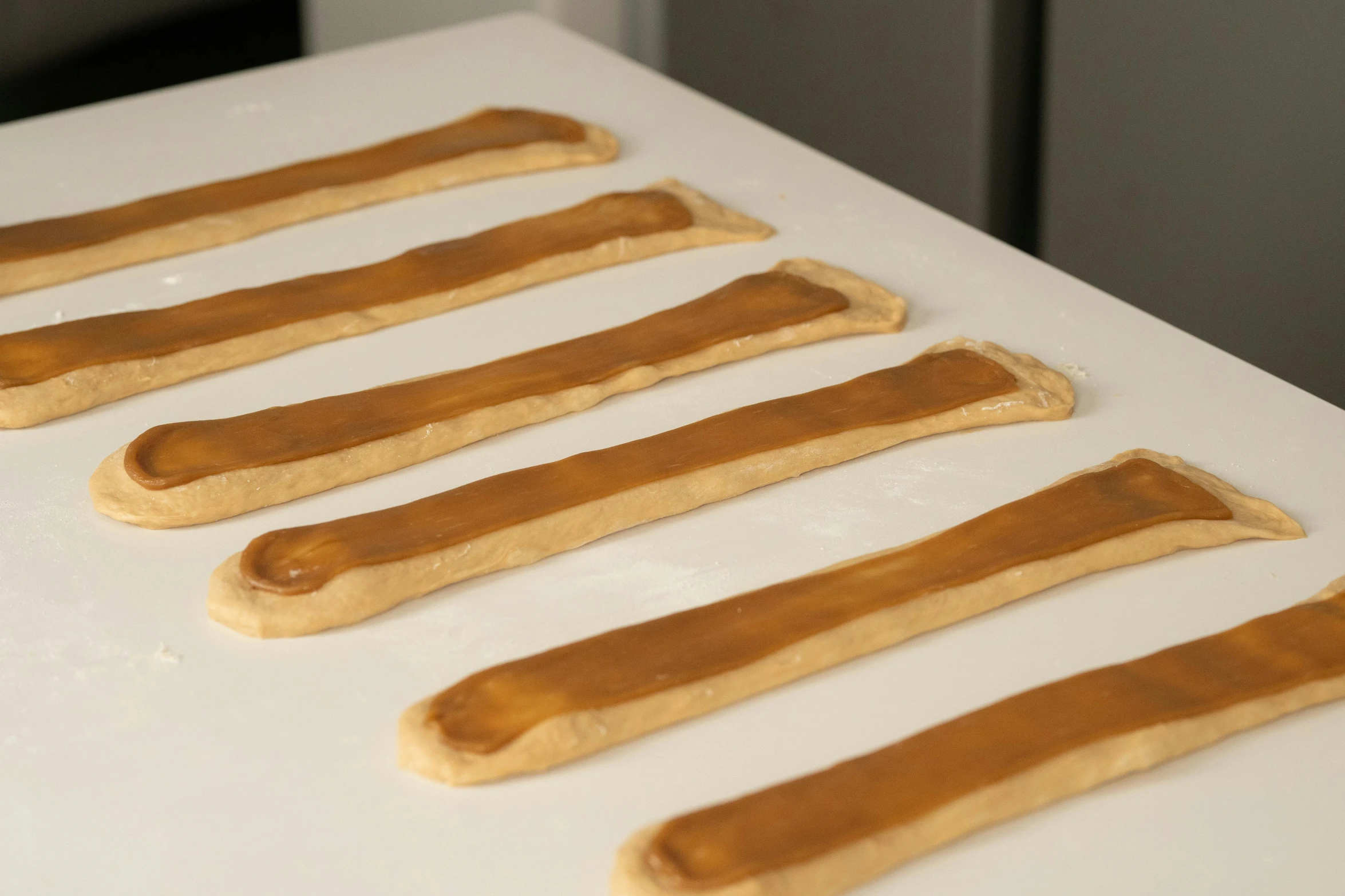 a row of peanut butter dog treats sitting on top of a counter, inspired by Richmond Barthé, process art, very long arms, plating, smooth panelling, pour paint