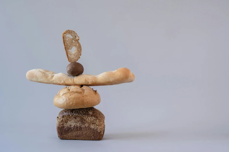 a bunch of bread stacked on top of each other, a surrealist sculpture, inspired by Jan Kupecký, unsplash, balancing the equation, floating pieces, anthropomorphic edible piechart, natural materials