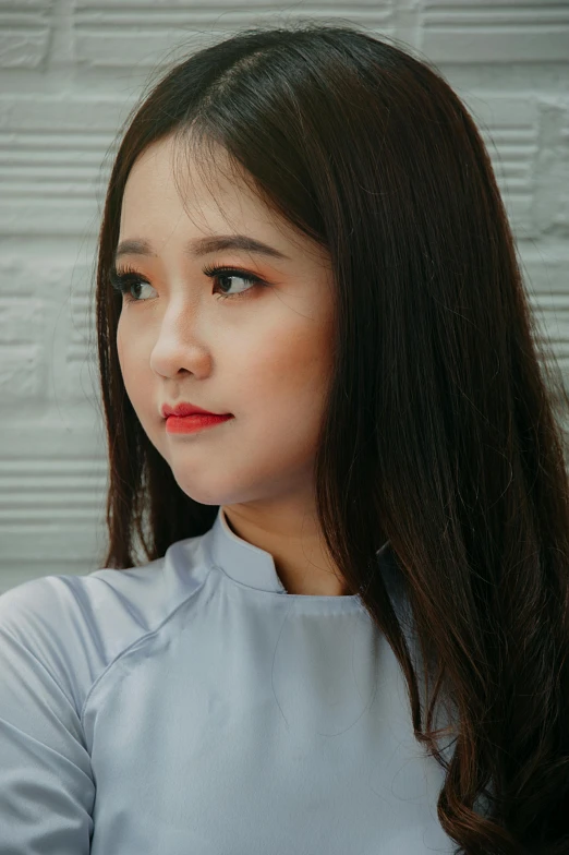 a woman holding a cell phone up to her ear, an album cover, inspired by Ruth Jên, trending on pexels, realism, vietnamese woman, square nose, young with long hair, wearing a light blue shirt