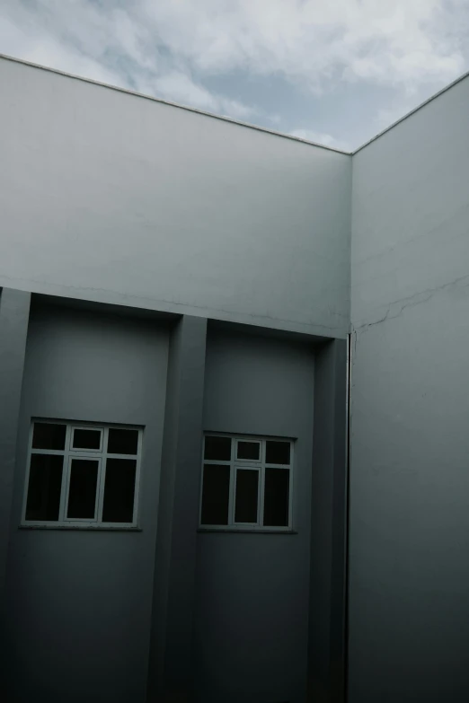 a man riding a skateboard up the side of a building, a minimalist painting, inspired by Paul Lucien Dessau, postminimalism, soviet yard, grey sky, low quality photograph, windows and walls :5