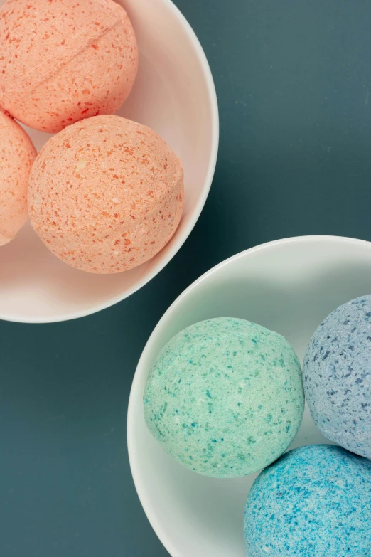 three bowls of bath bombs on a table, male and female, zoomed in, blueberry and orange and teal, thumbnail