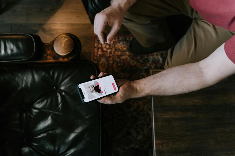 a man sitting on a couch holding a cell phone, a picture, pexels contest winner, tinder profile, on a table, avatar image, high resolution image