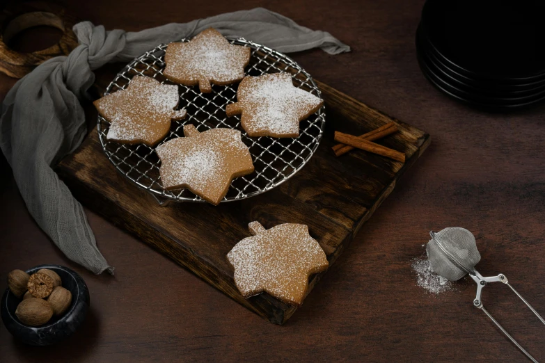 a wooden cutting board topped with cookies covered in powdered sugar, inspired by Richmond Barthé, hurufiyya, canadian maple leaves, product view, cinnamon, 3 4 5 3 1