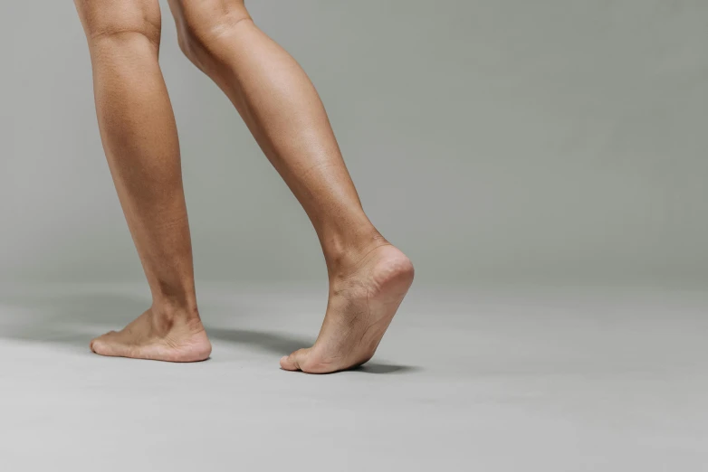 a close up of a person's legs and legs, on grey background, cantered, barefoot, slightly tanned