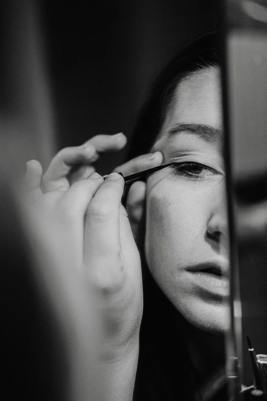 a woman putting on mascara in front of a mirror, a black and white photo, inspired by Marina Abramović, pexels contest winner, hyperrealism, brittney lee, photography hyperrealism, eyelids, woman