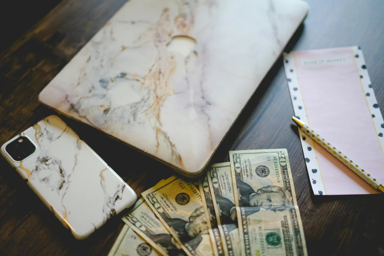 a laptop computer sitting on top of a wooden table, a marble sculpture, trending on pexels, made of money, marbled veins, thumbnail, bags of money