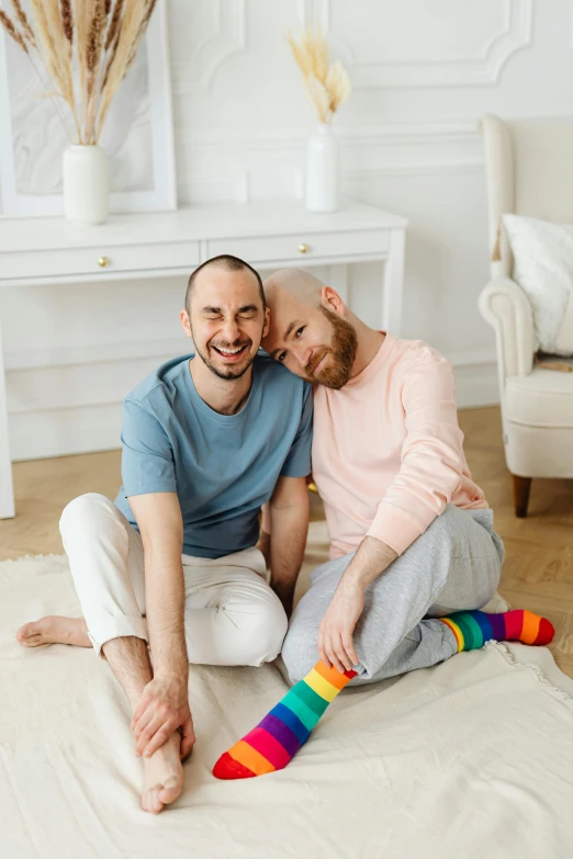 a man and a woman are sitting on the floor, a photo, shutterstock, ( ( ( rainbow ) ) ), two buddies sitting in a room, bald, dasha taran