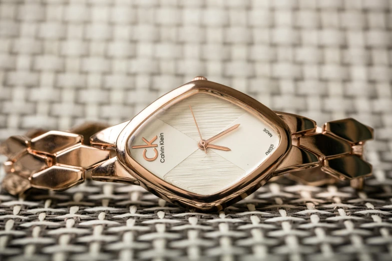 a close up of a watch on a table, trending on cg society, arabesque, reflections in copper, calvin klein, thumbnail, square