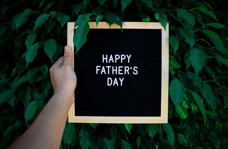 a person holding a sign that says happy father's day, pexels contest winner, black, instagram post, billboard image, felt