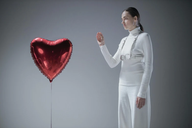 a woman standing next to a heart shaped balloon, inspired by Marina Abramović, pexels contest winner, hyperrealism, movie still of a cyborg, hito steyerl, carice van houten, scene from the film