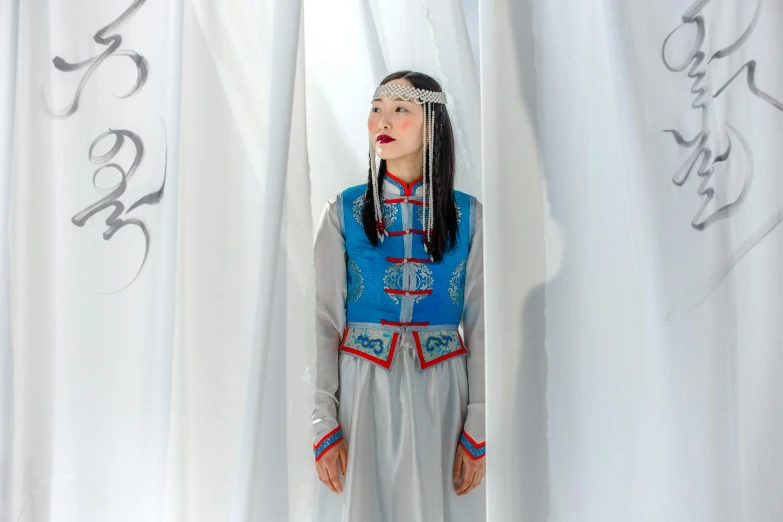 a woman that is standing in front of a curtain, inspired by Kim Tschang Yeul, hurufiyya, costume with blue accents, inuk, white sky, silver and blue colors