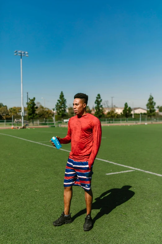 a man standing on top of a soccer field, hydration, red and blue garments, working out, evan lee