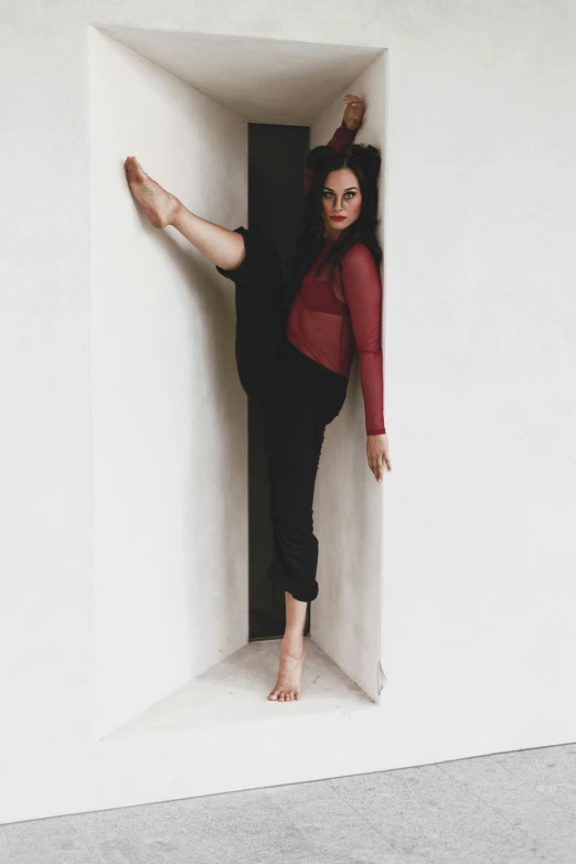 a woman that is standing in a box, inspired by Elizabeth Polunin, unsplash, arabesque, leaning against the wall, low quality photo, instagram photo, red and black