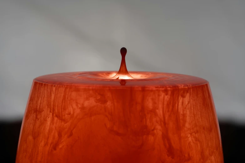 a close up of a lit candle on a table, inspired by Anish Kapoor, dribble, burnt sienna and venetian red, 3/4 view from below, gourd, fountain of water