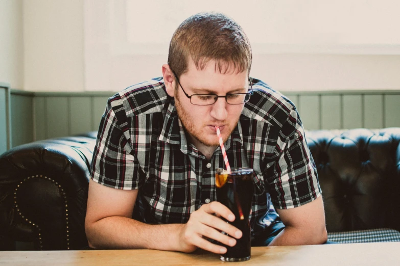 a man sitting at a table with a drink in his hand, a portrait, by Joe Bowler, unsplash, an overweight, aged 2 5, profile image, soda