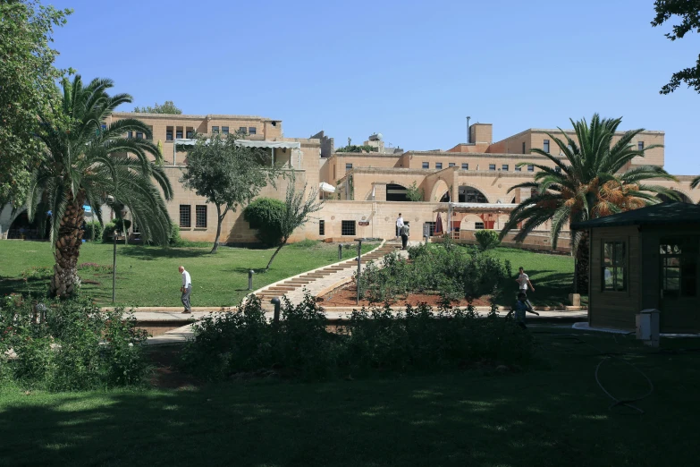 a large building sitting on top of a lush green field, by Edward Ben Avram, old town mardin, exterior botanical garden, rammed earth courtyard, school courtyard