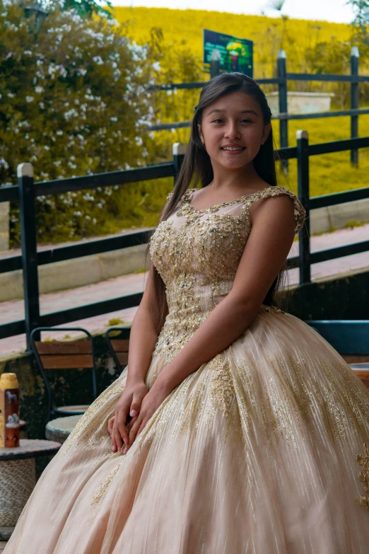 a woman in a ball gown sitting on a bench, by reyna rochin, pexels contest winner, a beautiful teen-aged girl, sitting on a mocha-colored table, gold encrustations, she is mexican