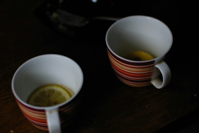 a couple of cups sitting on top of a wooden table, lemon, unedited, image, small